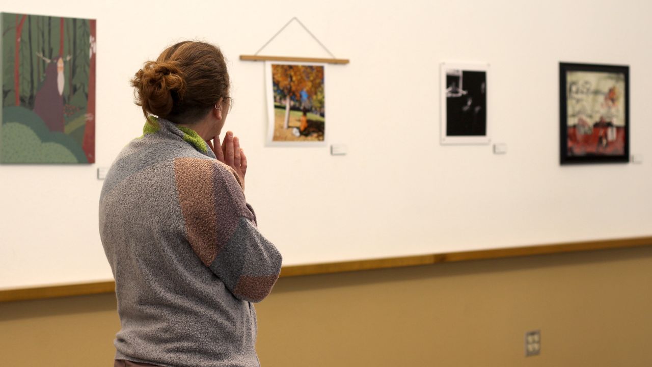 Associate Professor Amaris Feland Ketcham admires artwork.