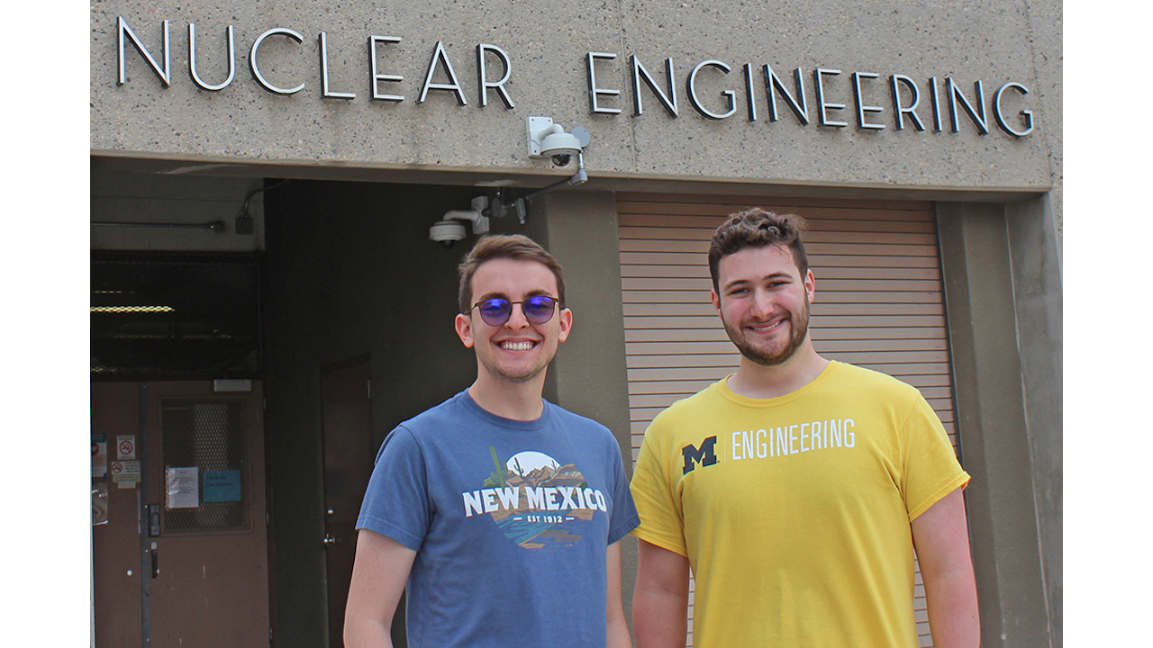 Justin Hamil and Ethan Krammer stand in front of the Nuclear Engineering Building with shirts designating their graduate school destinations.