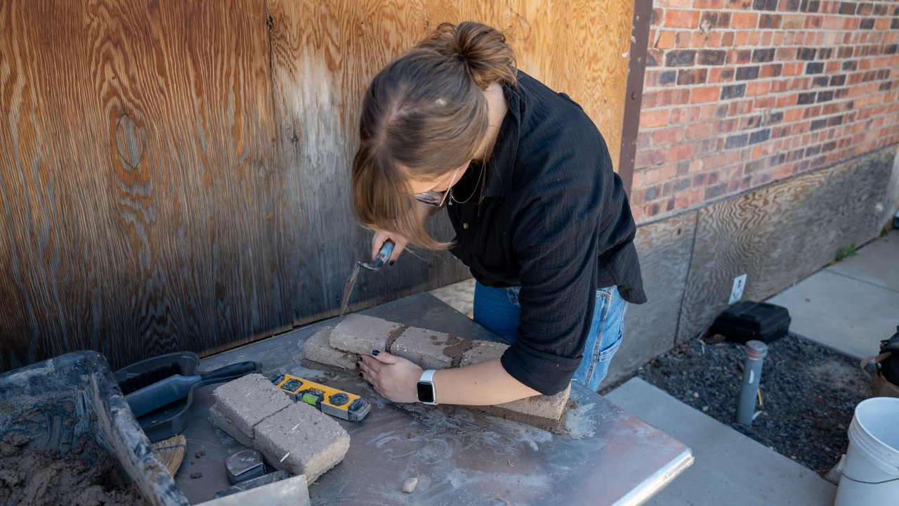Student assembling adobe brick wall 