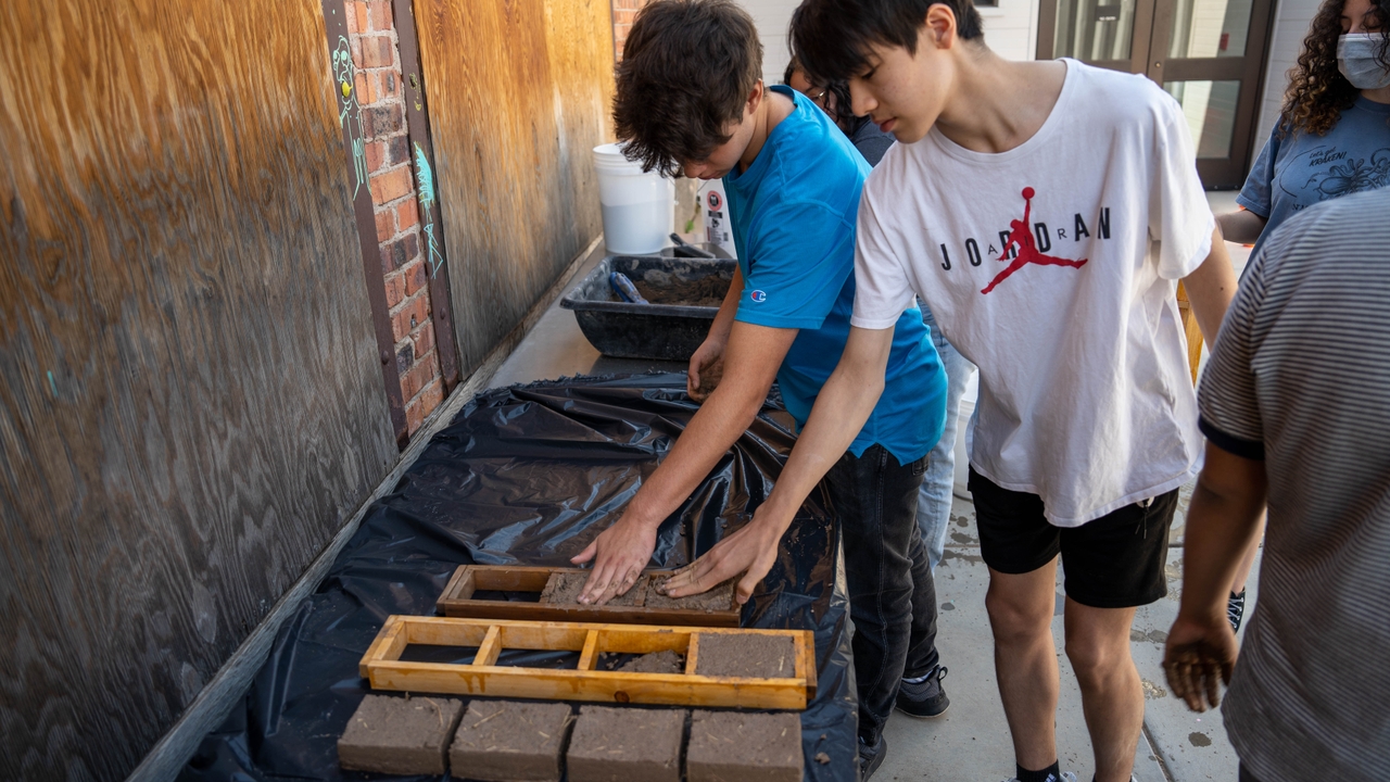 Two students working together to build adobe