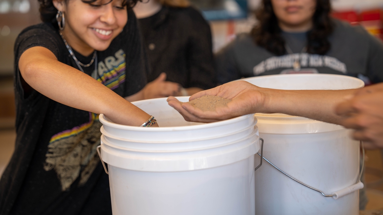 Students exploring sand mixture for adobe making