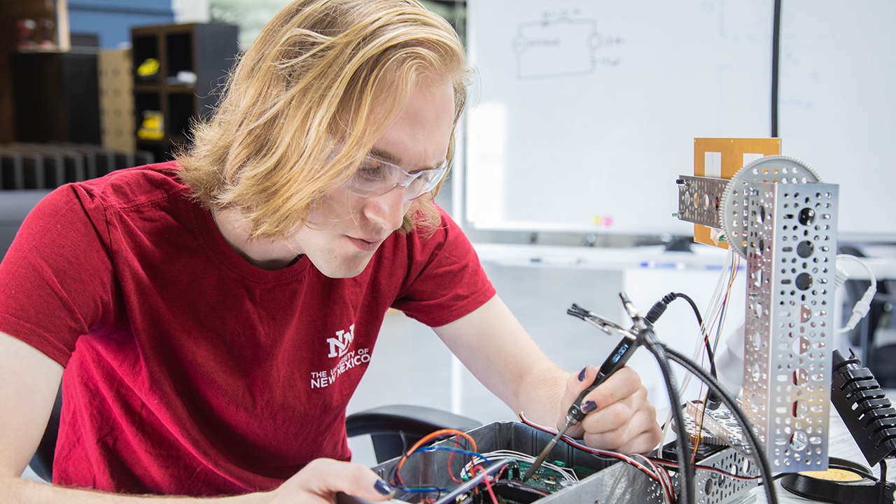A UNM student works on electronics.