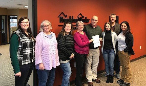Bill Kopka (fourth from the right) presents the $15,000 donation on behalf of Associated Bank to NeighborWorks Green Bay.