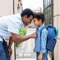 Smiling father leaving son with backpack to school