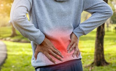 Sport man suffering from backache at park outdoors, Lower back pain concept