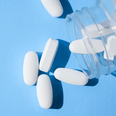 Oxycodone pills. Opioid pain medication, narcotic. Close up white pills with a bottle on a blue background