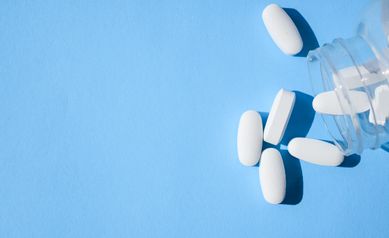 Oxycodone pills. Opioid pain medication, narcotic. Close up white pills with a bottle on a blue background
