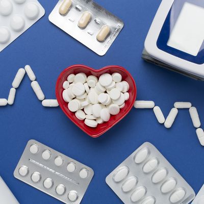 Cardiogram made with medicines and heart-shaped bowl on color background, top view