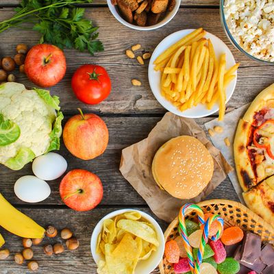 Fastfood and healthy food on old wooden background. Concept choosing correct nutrition or of junk eating. Top view.