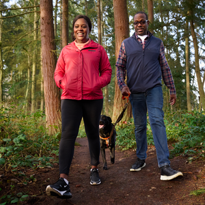 Monique and her husband walking with their dog in the woods